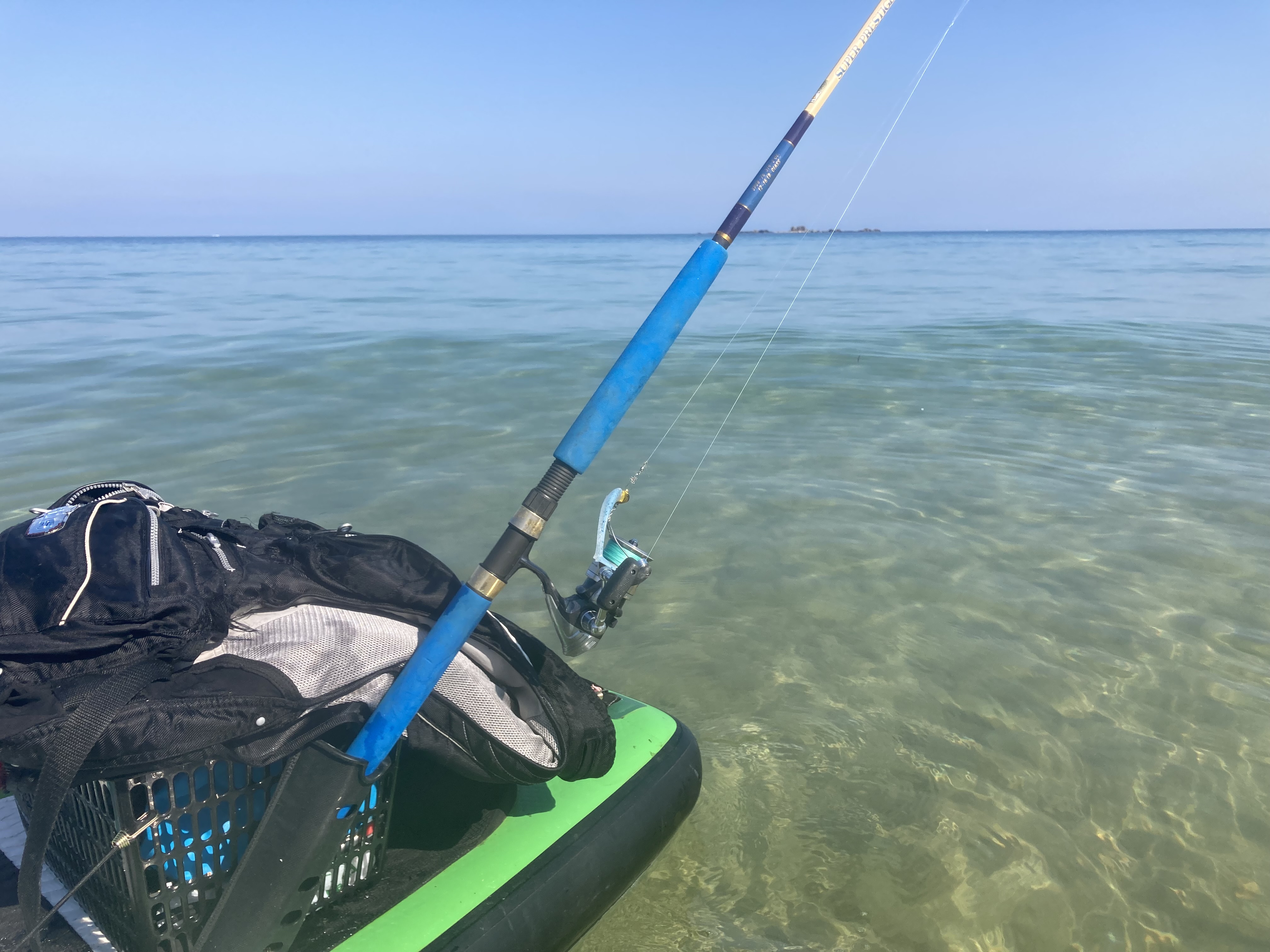 澄んだ海と青空。SUPボードの上から竿を構えて。